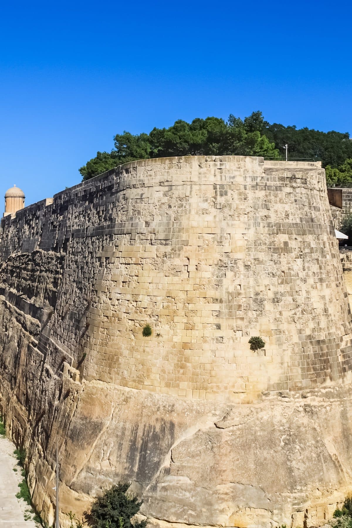 The honey-coloured bastion walls of Valletta's fortifications rising against a deep blue sky.